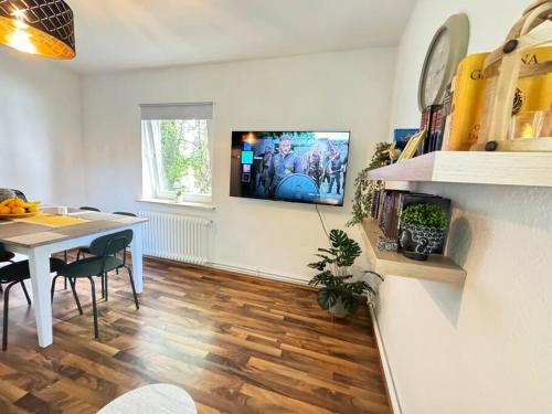 un salon avec une table et une télévision murale dans l'établissement Complete All Inclusive Apartment+Netflix, à Wilhelmshaven