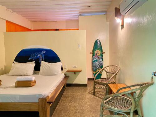 une chambre avec un lit et une planche de surf sur le mur dans l'établissement Lexias Hostel and Workspace - Siargao, à Catagnan
