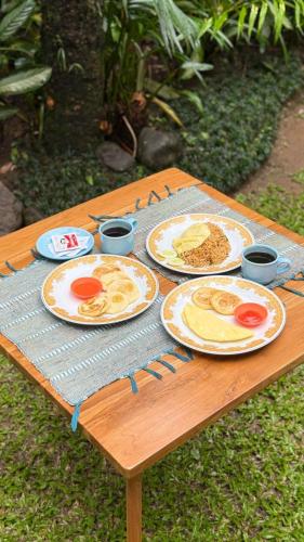 ein Holztisch mit Tellern voller Essen darauf in der Unterkunft Vaneka Garden House in Ubud