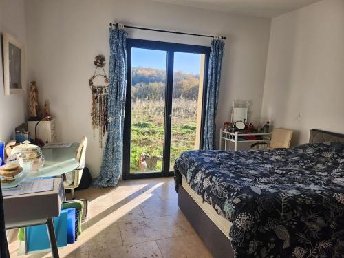 a bedroom with a bed and a sliding glass door at Viviloue in Saint-Pierre-Lafeuille