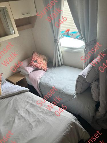 two beds in a small room with a window at Sunset Walk 046 in Barmouth