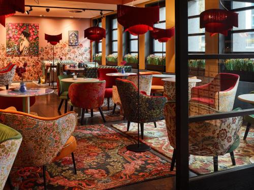 ein Restaurant mit Tischen, Stühlen und roten Lampen in der Unterkunft 25hours Hotel The Goldman in Frankfurt am Main