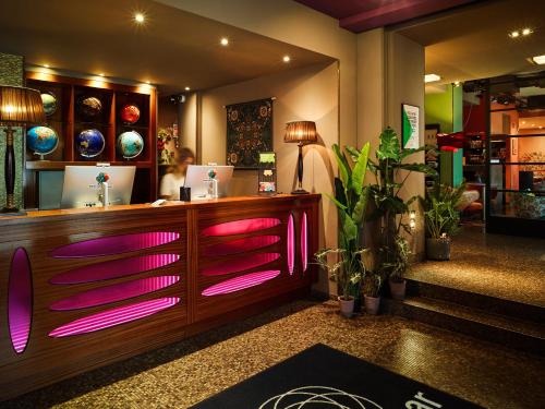 ein Restaurant mit rosafarbenen Lichtern an der Theke in der Unterkunft 25hours Hotel The Goldman in Frankfurt am Main