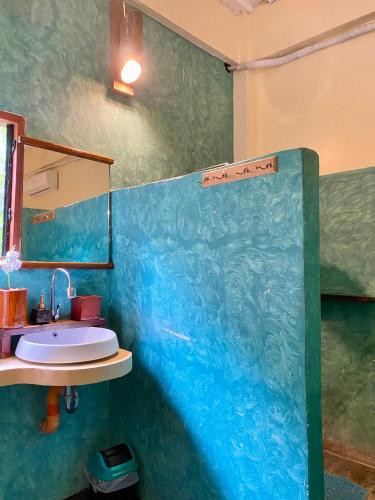 a blue bathroom with a sink and a mirror at Lexias Hostel and Workspace - Siargao in Catagnan
