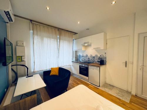ein Wohnzimmer mit einer blauen Couch und einer Küche in der Unterkunft Le New Daily, 500m du centre de Dax in Dax