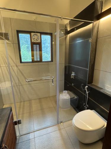 baño con ducha, aseo y reloj en Sibees Garden, en Kattappana