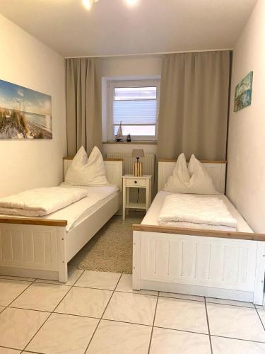a bedroom with two beds and a window at NTBM36002-FeWo-Kiekut in Neue Tiefe Fehmarn