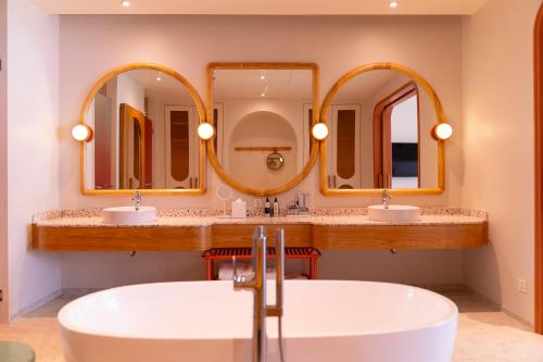 a bathroom with two sinks and two mirrors at The Standard, Pattaya Na Jomtien in Na Jomtien