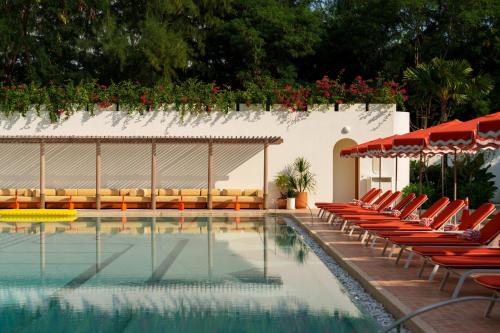 a swimming pool with red chairs and umbrellas at The Standard, Pattaya Na Jomtien in Na Jomtien