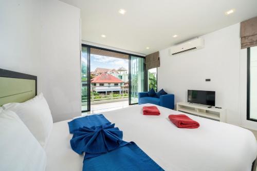 ein Schlafzimmer mit einem weißen Bett mit blauem Bogen in der Unterkunft 3-Story Pool Villa Near Kata Beach - UTK 4 in Kata Beach
