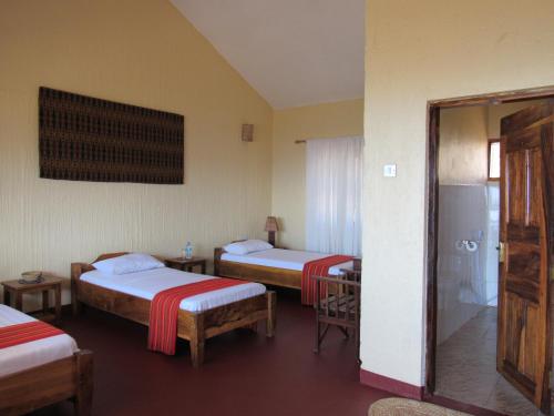 a room with three beds and a shower in it at African Sunrise Lodge and Campsite in Mto wa Mbu