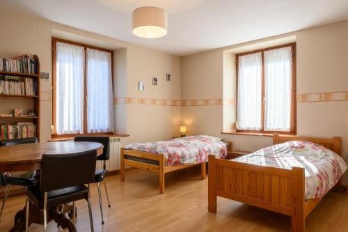1 dormitorio con mesa, cama, mesa y sillas en Le Gîte À Mamie, en Orbey