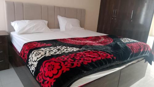 Spacious 2-Bedroom Apartment with Terrace & Multiple Bathrooms في Dargai: سرير عليه بطانية سوداء وحمراء