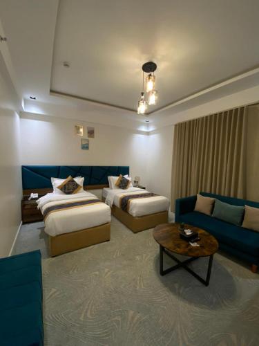 a hotel room with two beds and a couch at Sunset Hotel for Hotel Services in Najran