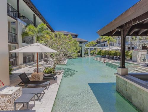 a swimming pool at a resort with chairs and an umbrella at Coastal Bliss Studio - Santai 224 in Casuarina