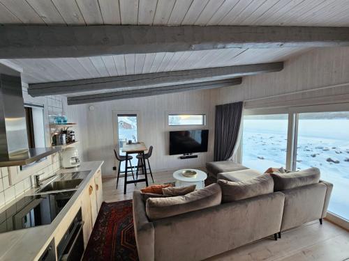 a living room with a large couch and a kitchen at Aurora Jukkas Riverside Lodge in Jukkasjärvi