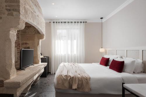 a bedroom with a large white bed with red pillows at Civitas Suites Hotel in Rethymno