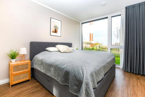a bedroom with a bed and a large window at BeltBlick 14- Küstenleuchten - Moderne Ferienwohnung direkt am Strand mit Sauna und Garten! in Fehmarn