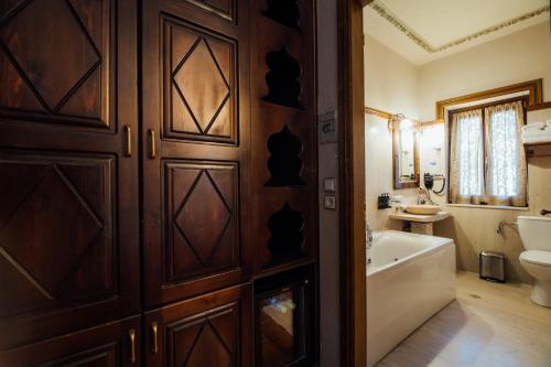 a bathroom with a wooden door and a tub and a sink at Archontiko Naoumidi in Portaria