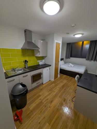 eine Küche mit einem Waschbecken und ein Zimmer mit einem Bett in der Unterkunft Modern Studio Apartment in Central Newcastle in Central Station