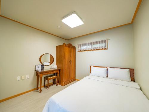 a bedroom with a bed and a mirror at Four Season Pension in Seogwipo