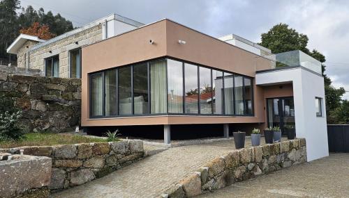 a house with glass windows and a stone wall at Villa Maragoça Retreat Douro in Portela