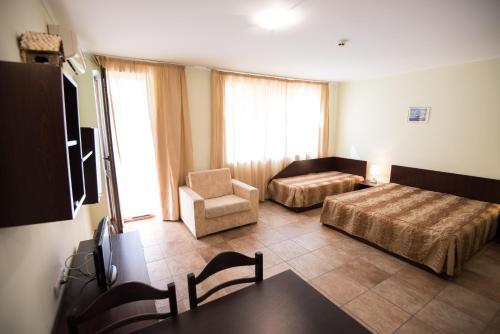 a hotel room with two beds and a chair at Family hotel Apolon in Nesebar