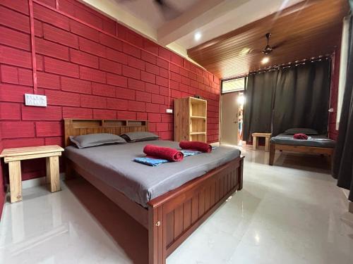 - une chambre avec un mur en briques rouges et un lit dans l'établissement Cocopelli Guest House, à Gokarna