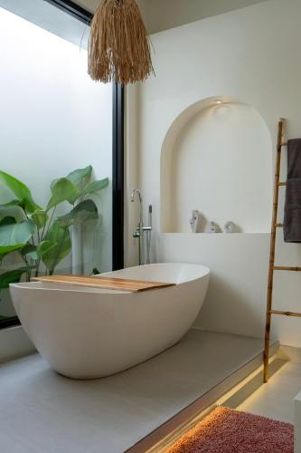 a bathroom with a white tub and a plant at Tanahlot Beachview Rooftop Villa in Tanah Lot