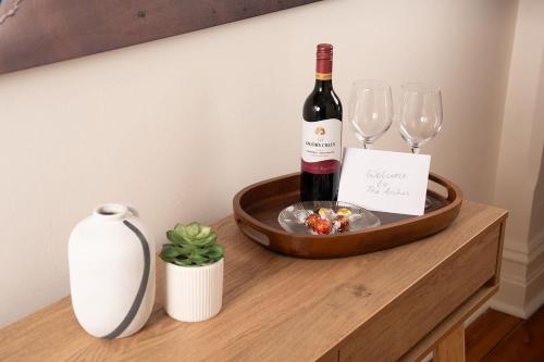 a bottle of wine and glasses on a wooden table at The Arches- Beautiful 3-Bedroom Family Stay Near Adelaide Oval, City Events and Amazing Dining in North Adelaide