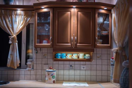a kitchen with wooden cabinets and a tiled wall at Ourdreamhouses Lake Hereou Loutraki in Vouliagmeni Lake