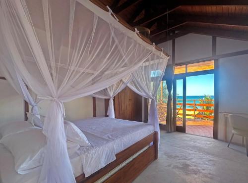 a bedroom with a canopy bed with a view of the ocean at Índico Breeze in Praia do Tofo