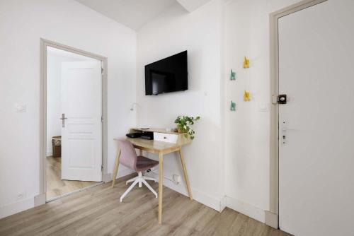 een kamer met een bureau en een tv aan de muur bij Appartement cozy au centre-ville in Brest