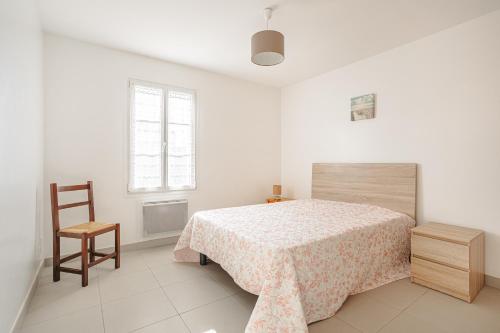 ein weißes Schlafzimmer mit einem Bett und einem Stuhl in der Unterkunft Villa Du Chai in Sainte-Marie-de-Ré