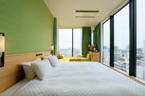 a bedroom with a large bed with large windows at Candeo Hotels Hiroshima Hatchobori in Hiroshima