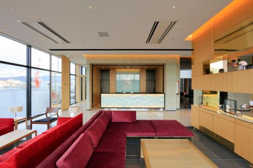 a living room with red couches and a counter at Candeo Hotels Hiroshima Hatchobori in Hiroshima