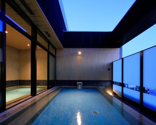 a swimming pool in a building with windows at Candeo Hotels Hiroshima Hatchobori in Hiroshima