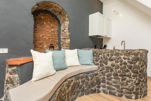 a couch in a living room with a brick wall at Gesuiti Home - Lumina Collection in Catania