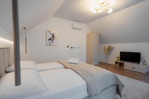 Zamkowy Zakątek - Luksusowe domki z jacuzzi في Nowy Wiśnicz: غرفة نوم بيضاء مع سرير وتلفزيون