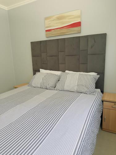 a bed with a white and black striped comforter at Blouberg Beach Gem 5 Min Walk in Cape Town