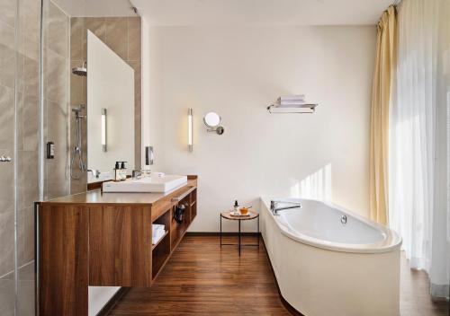 ein Badezimmer mit Badewanne, Waschbecken und Spiegel in der Unterkunft ABION Villa Suites in Berlin