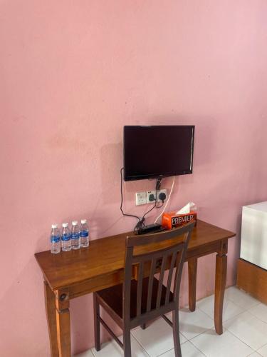 un bureau avec une télévision et des bouteilles d'eau dessus dans l'établissement Az Inn, à Pantai Cenang