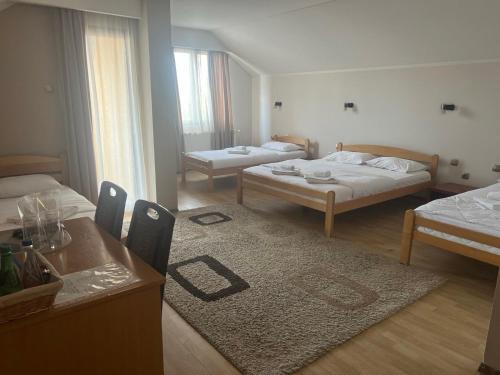 a room with two beds and a table with a rug at Guest house Vila Bor in Novi Sad