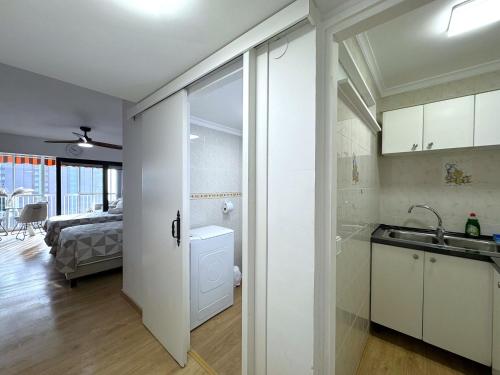 a white kitchen with a sink and a bedroom at Albatros 13º in Benidorm