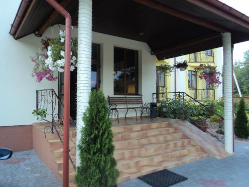 a porch of a house with a bench and flowers at Hotel Restaurant Vizit in Truskavets