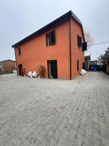 un grand bâtiment orange avec une grande allée dans l'établissement Affittacamere LA CASA DI GIADA a 5 minuti dal centro di Imola - parcheggio privato interno per furgoni e auto, à Imola