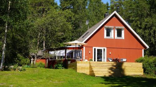 a red house with an umbrella on a green field at Landhaus Måsberget in Kristinehamn