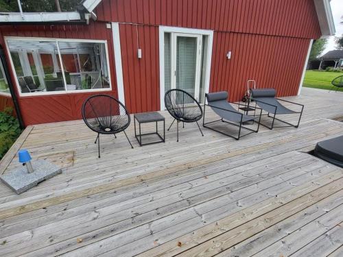 a deck with chairs and tables and a red building at Landhaus Måsberget in Kristinehamn