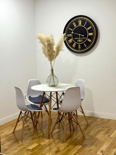 Una mesa con sillas y un reloj en la pared. en Apartman Mir, en Temerin