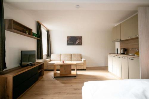 a living room with a couch and a tv and a kitchen at Ferienwohnung Mimosa 302 in Wiggensbach